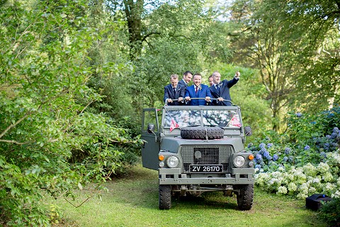 Groom arriving at the woodland wedding ceremony in a military Land Rover Lightweight